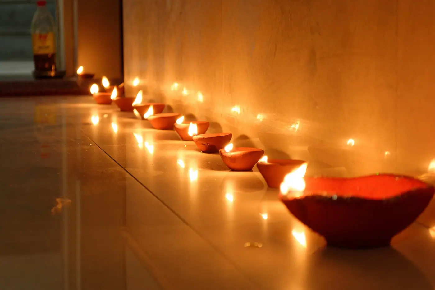 A row of lit clay diyas along the floor of a home on Diwali night