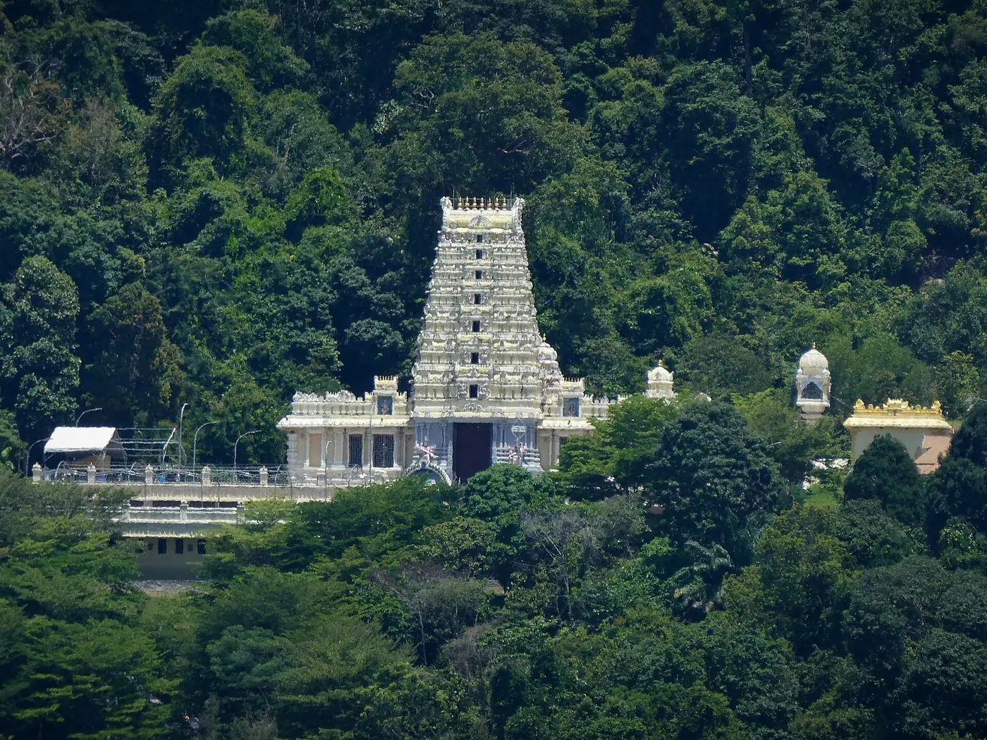 पेनांग के जॉर्ज टाउन में वनाच्छादित पहाड़ी के बीच वॉटरफ़ॉल हिलटॉप मंदिर का सफ़ेद और क्रीम रंग का गोपुरम और मुख्य सभागृह