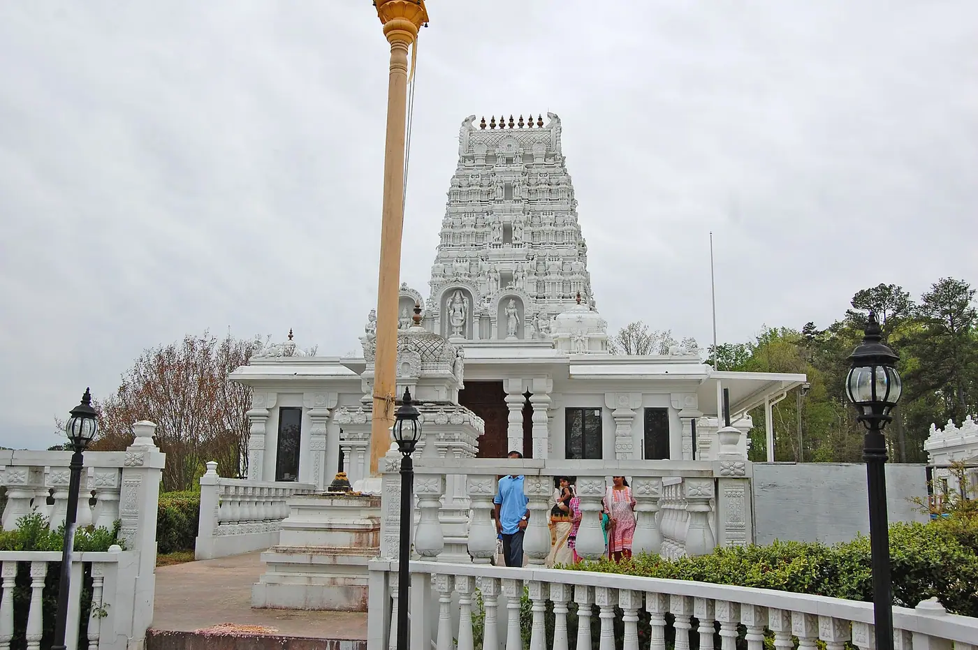जॉर्जिया के रिवरडेल में हिंदू टेंपल ऑफ अटलांटा के वेंकटेश्वर मंदिर का सफ़ेद बहुस्तरीय गोपुरम और प्रवेशद्वार, सामने ध्वजस्तंभ