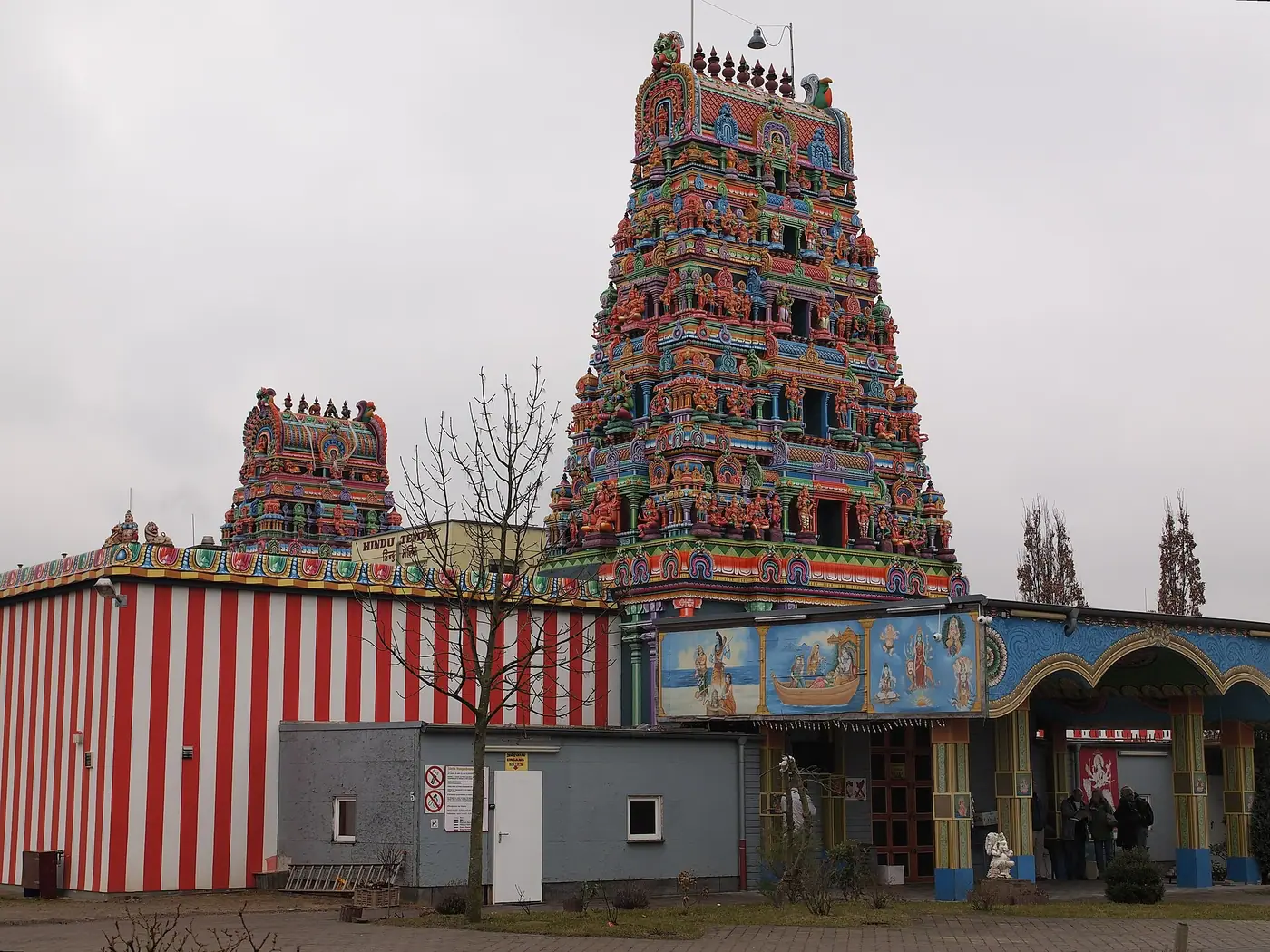 हाम-उएंट्रोप स्थित श्री कामाक्षी अम्मन मंदिर के प्रवेश द्वार पर रंगीन गोपुरम और लाल-सफ़ेद धारियों वाली बाहरी दीवार