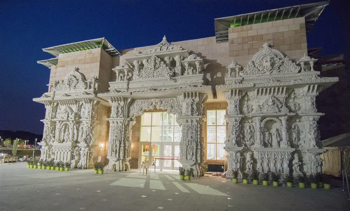 Carved white stone entrance of the BAPS Swaminarayan Akshardham mandir in Robbinsville, New Jersey, seen at dusk